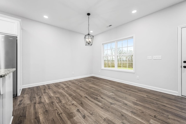 unfurnished dining area with a notable chandelier, recessed lighting, dark wood-style flooring, and baseboards