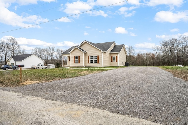 ranch-style house featuring gravel driveway, a front yard, and central air condition unit