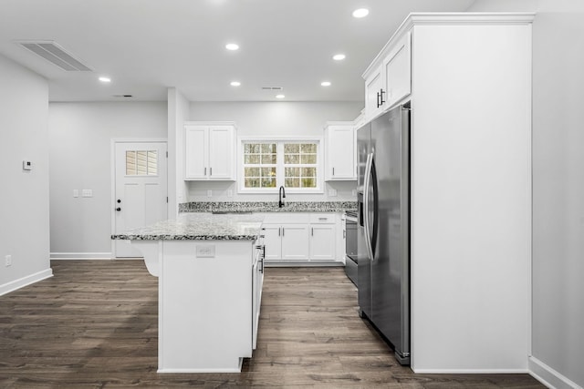 kitchen featuring visible vents, a kitchen island, recessed lighting, stainless steel fridge, and white cabinets