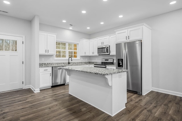 kitchen with visible vents, white cabinetry, stainless steel appliances, and light stone countertops