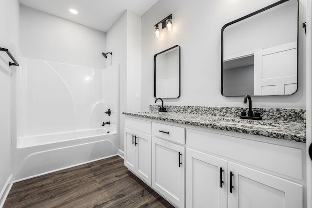 full bathroom featuring  shower combination, wood finished floors, double vanity, and a sink