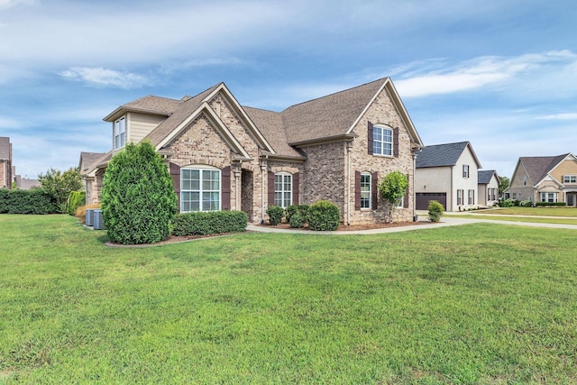 view of front of home with a shingled roof, a front yard, brick siding, and central AC