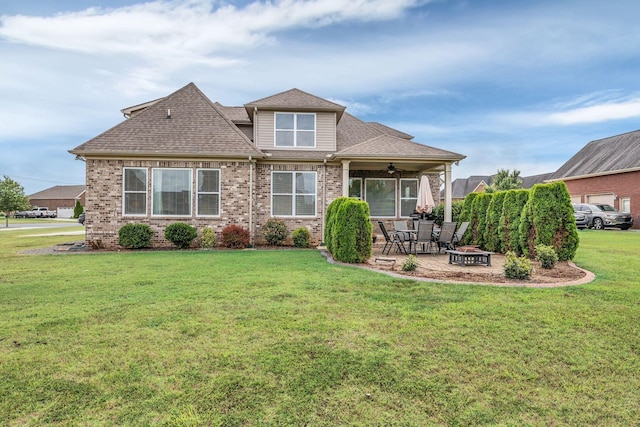 rear view of property featuring a patio, ceiling fan, a yard, and a fire pit