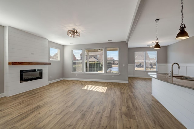 unfurnished living room with hardwood / wood-style floors, a fireplace, an inviting chandelier, and sink