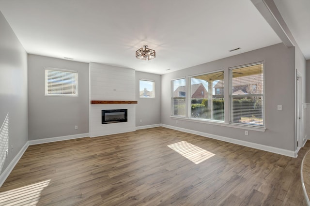 unfurnished living room with a fireplace, a chandelier, and wood-type flooring