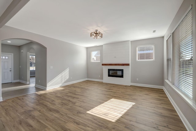 unfurnished living room featuring an inviting chandelier, a large fireplace, and light hardwood / wood-style flooring