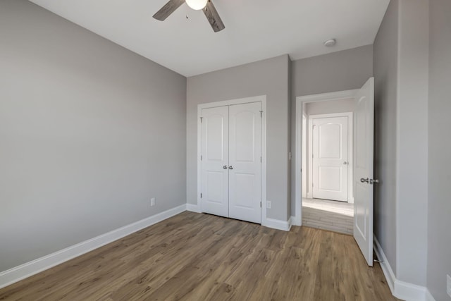 unfurnished bedroom featuring ceiling fan, a closet, and wood-type flooring