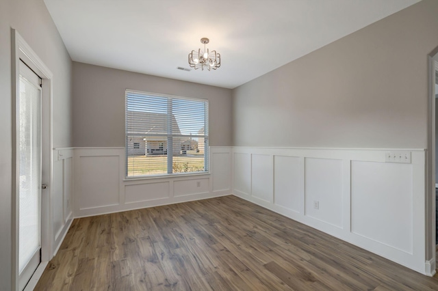 unfurnished room featuring dark hardwood / wood-style flooring and an inviting chandelier