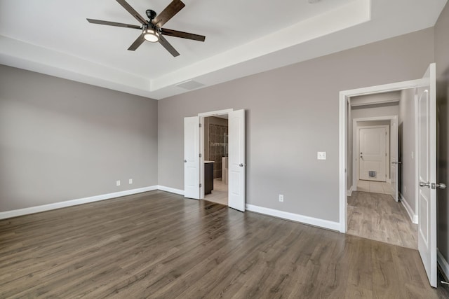 unfurnished bedroom featuring ceiling fan, a tray ceiling, and dark hardwood / wood-style flooring