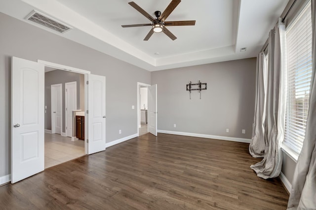 spare room featuring a raised ceiling, ceiling fan, and dark hardwood / wood-style floors