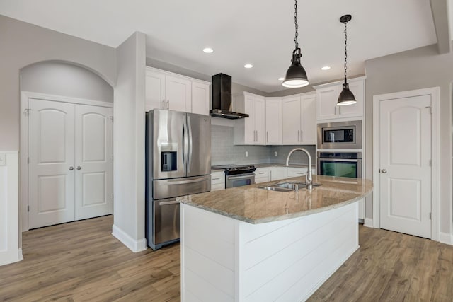 kitchen featuring sink, white cabinetry, an island with sink, wall chimney range hood, and appliances with stainless steel finishes