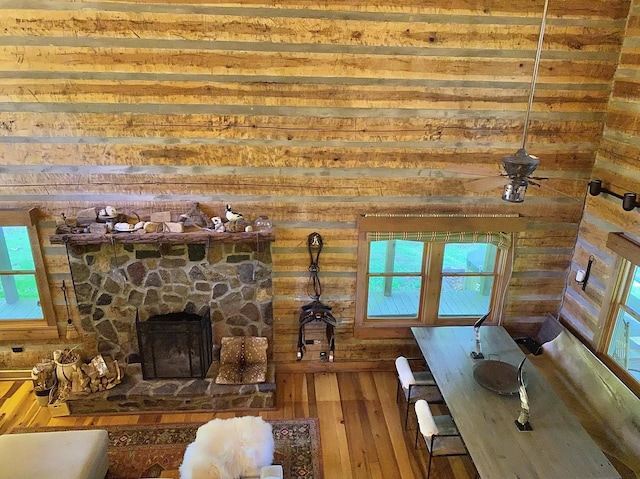 unfurnished living room with hardwood / wood-style floors, ceiling fan, a stone fireplace, and a wealth of natural light