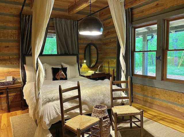 bedroom with hardwood / wood-style flooring, wooden walls, and multiple windows