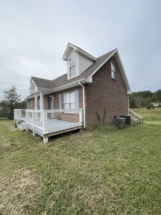 view of side of property featuring a yard, a deck, and central AC unit