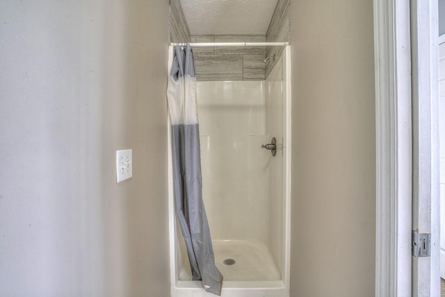 bathroom with curtained shower and a textured ceiling