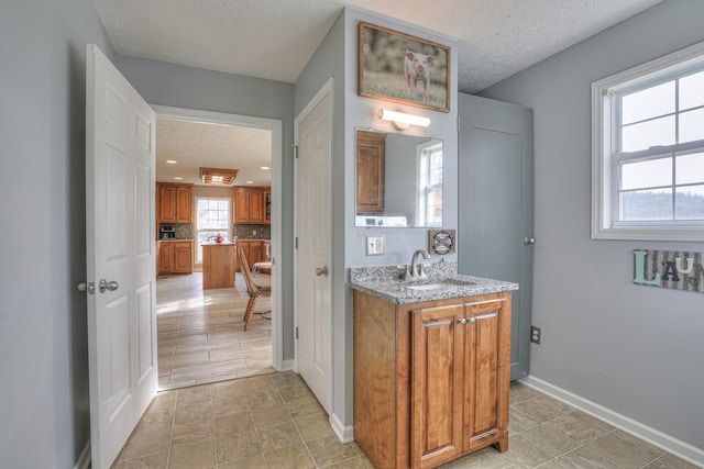 bathroom featuring vanity, a textured ceiling, a wealth of natural light, and tasteful backsplash