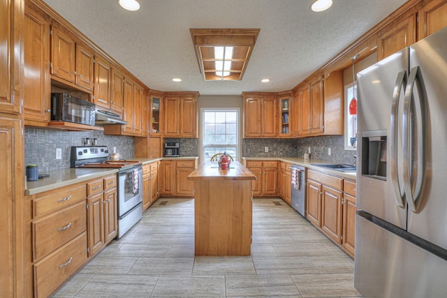 kitchen with tasteful backsplash, a textured ceiling, stainless steel appliances, sink, and a kitchen island