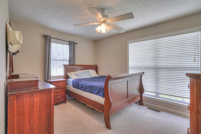 carpeted bedroom featuring ceiling fan and a textured ceiling