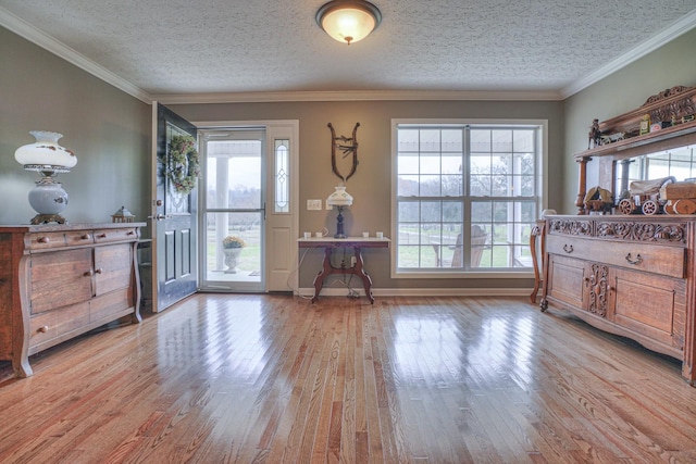 entrance foyer featuring plenty of natural light, light hardwood / wood-style floors, a textured ceiling, and ornamental molding