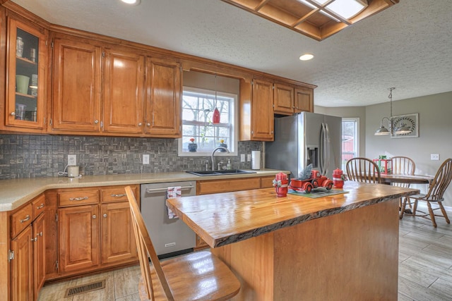 kitchen featuring sink, a center island, butcher block countertops, light hardwood / wood-style floors, and appliances with stainless steel finishes