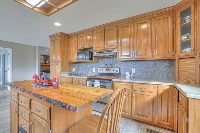 kitchen with backsplash, a center island, light hardwood / wood-style floors, and stainless steel electric range