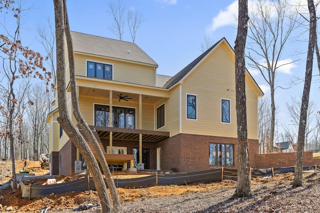 rear view of property with ceiling fan, brick siding, and a balcony