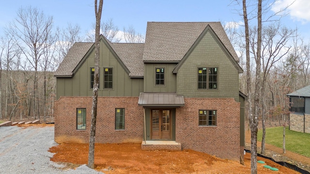 view of front of home featuring board and batten siding, brick siding, and roof with shingles