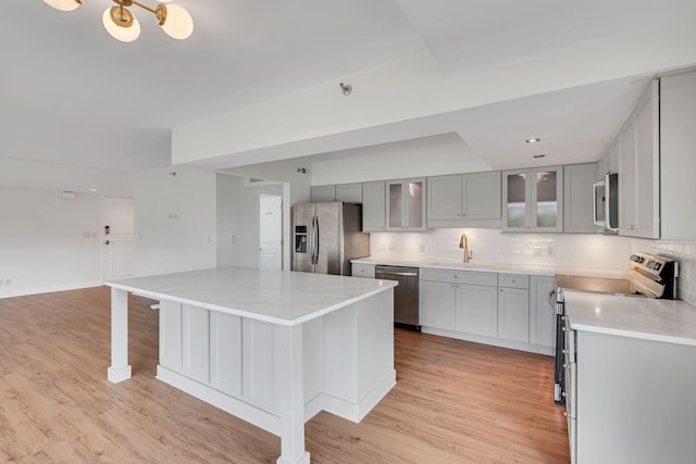 kitchen featuring decorative backsplash, a kitchen island, stainless steel appliances, and light hardwood / wood-style floors