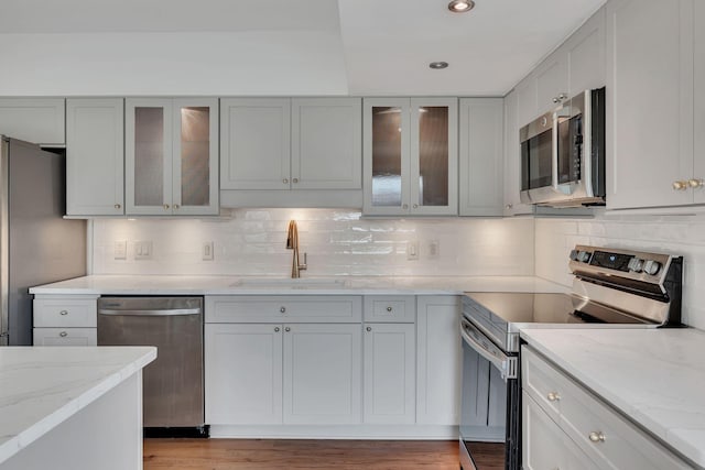 kitchen featuring light stone counters, sink, appliances with stainless steel finishes, and light hardwood / wood-style flooring