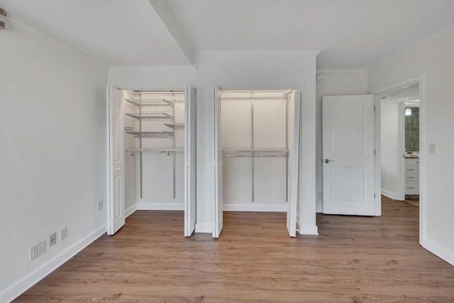 unfurnished bedroom featuring light wood-type flooring, crown molding, and a closet