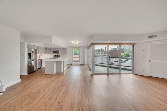 kitchen with a breakfast bar area, light hardwood / wood-style flooring, a kitchen island, and appliances with stainless steel finishes