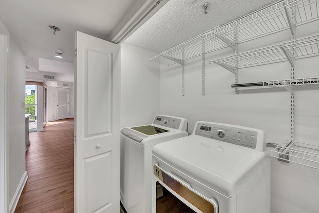 laundry room featuring washing machine and clothes dryer and hardwood / wood-style flooring