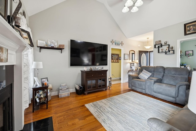 living room featuring high vaulted ceiling, a fireplace, wood finished floors, a ceiling fan, and baseboards