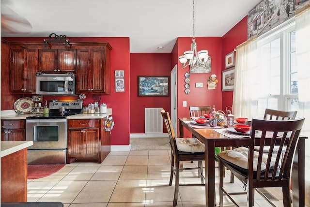 kitchen featuring light tile patterned floors, visible vents, appliances with stainless steel finishes, hanging light fixtures, and light countertops