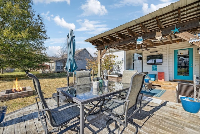 wooden terrace with ceiling fan, outdoor dining space, and an outdoor fire pit