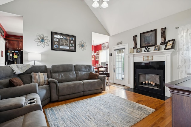 living area with a fireplace with flush hearth, high vaulted ceiling, and wood finished floors