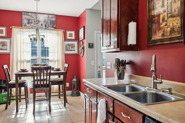 kitchen featuring pendant lighting, a notable chandelier, light countertops, light tile patterned flooring, and a sink