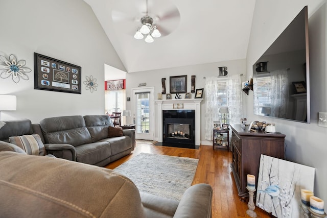 living room with a fireplace with flush hearth, high vaulted ceiling, wood finished floors, and a ceiling fan