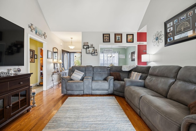 living room with high vaulted ceiling, wood finished floors, and baseboards