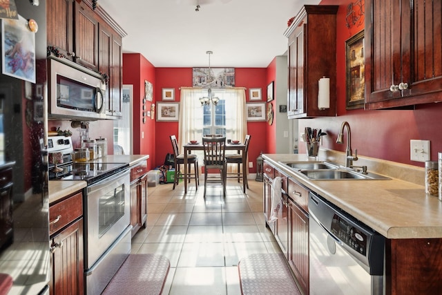 kitchen with light tile patterned floors, appliances with stainless steel finishes, decorative light fixtures, light countertops, and a sink