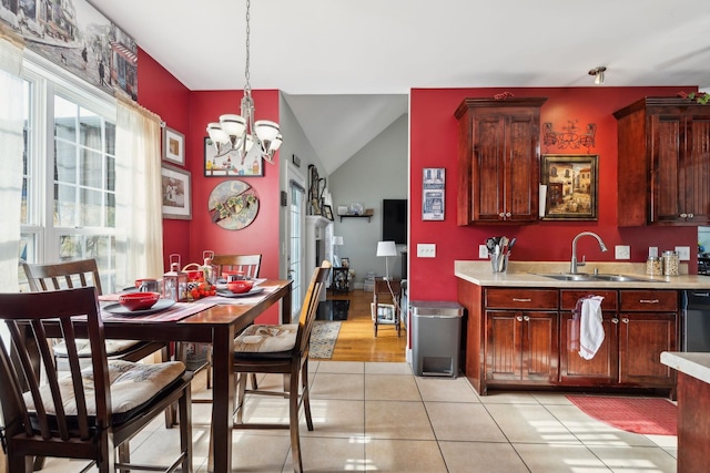 kitchen with light tile patterned floors, lofted ceiling, decorative light fixtures, light countertops, and a sink