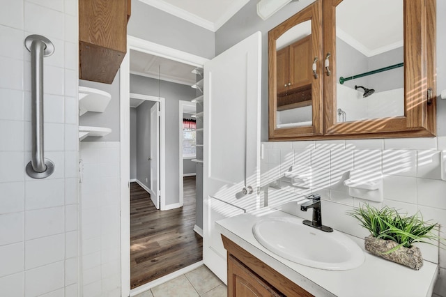 bathroom featuring tiled shower, hardwood / wood-style floors, vanity, and ornamental molding