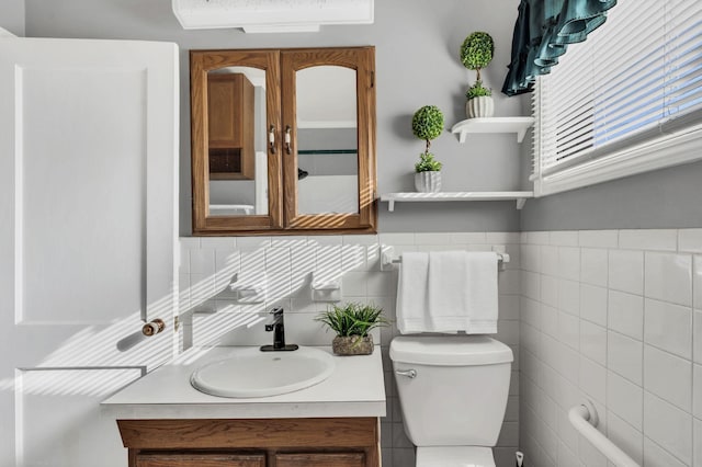 bathroom featuring vanity, tile walls, and toilet