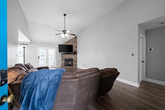 living room featuring ceiling fan, a stone fireplace, lofted ceiling, and dark wood-type flooring