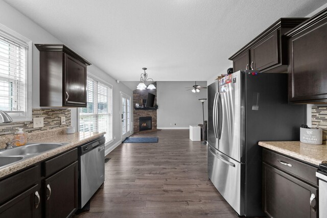 kitchen featuring a stone fireplace, dark hardwood / wood-style flooring, stainless steel appliances, and tasteful backsplash