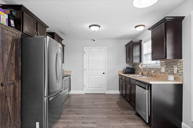 kitchen featuring sink, dark wood-type flooring, stainless steel appliances, tasteful backsplash, and dark brown cabinets