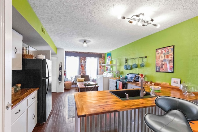 interior space featuring sink, dark hardwood / wood-style flooring, a textured ceiling, and washer / dryer