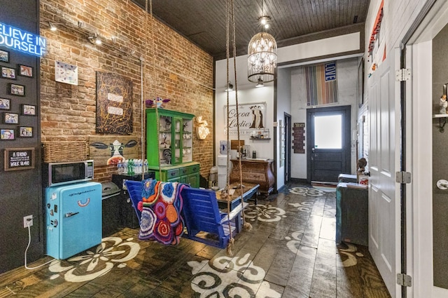 interior space featuring a towering ceiling, a notable chandelier, and brick wall