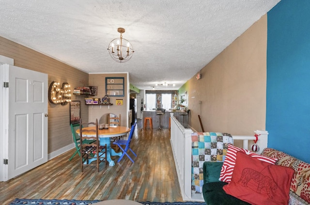 dining area with a textured ceiling, hardwood / wood-style flooring, and an inviting chandelier