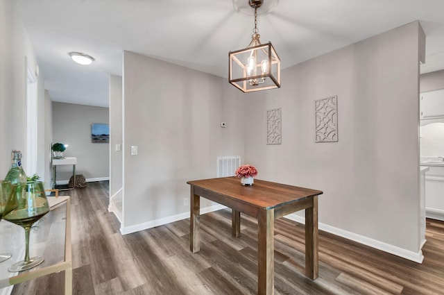 dining space with dark hardwood / wood-style floors and a chandelier